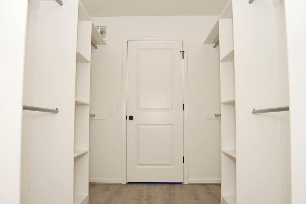 Example of a mid-sized classic gender-neutral light wood floor and beige floor walk-in closet design in Kansas City with open cabinets and white cabinets