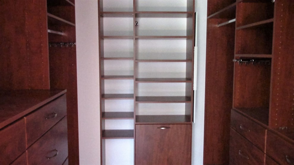 Modelo de armario vestidor unisex clásico de tamaño medio con puertas de armario de madera oscura, armarios con paneles lisos, suelo de madera en tonos medios y suelo marrón