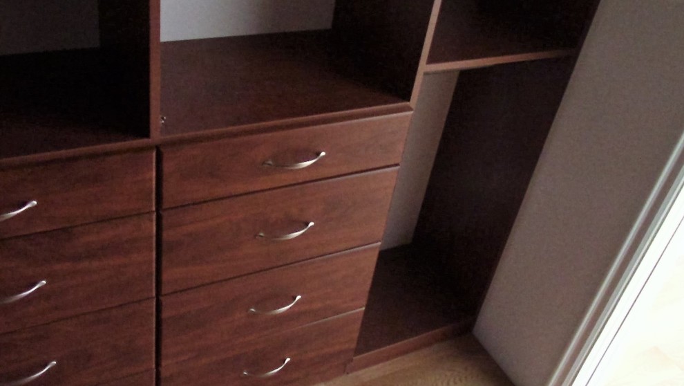 This is an example of a medium sized classic gender neutral walk-in wardrobe in Los Angeles with medium wood cabinets, flat-panel cabinets, medium hardwood flooring and brown floors.
