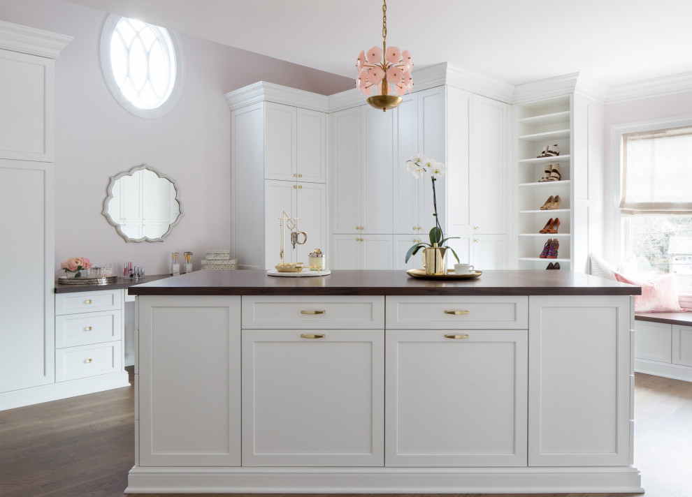 Inspiration for a traditional dressing room for women in New York with shaker cabinets, white cabinets, medium hardwood flooring and brown floors.