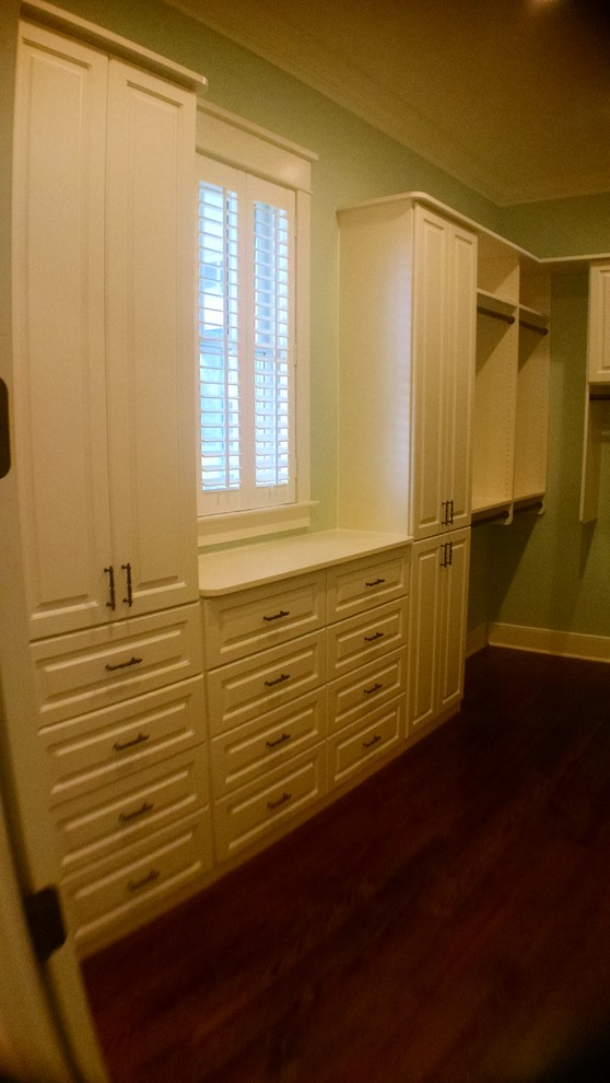 Пример оригинального дизайна: гардеробная комната в классическом стиле с фасадами с выступающей филенкой, белыми фасадами и темным паркетным полом