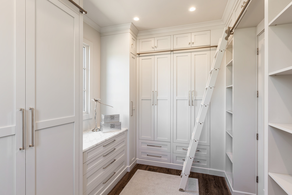 Walk-in closet - large gender-neutral medium tone wood floor and brown floor walk-in closet idea in Other with beaded inset cabinets and white cabinets