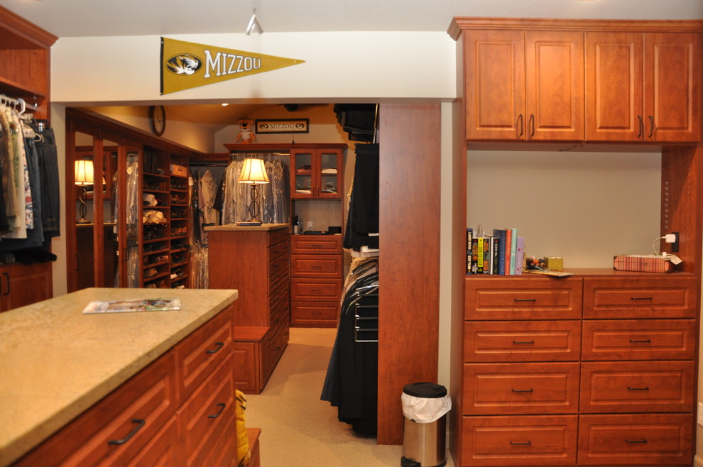 Example of a huge classic carpeted walk-in closet design in Other with raised-panel cabinets and medium tone wood cabinets