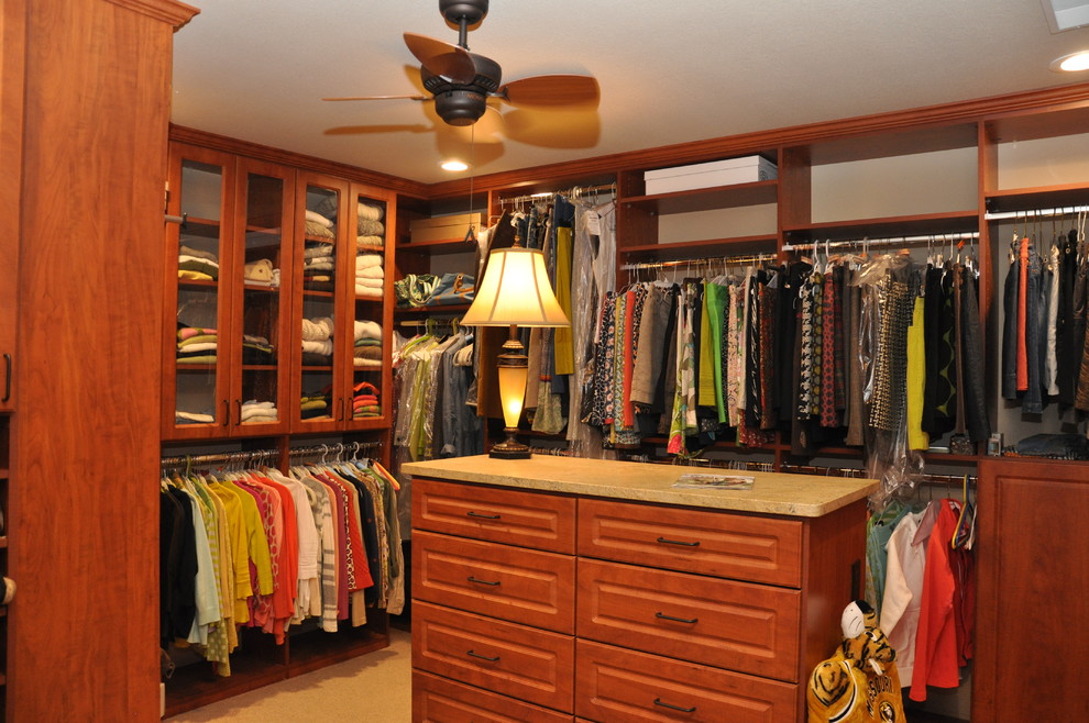 Großer Begehbarer Kleiderschrank mit profilierten Schrankfronten, hellbraunen Holzschränken und Teppichboden in Sonstige