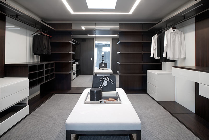 Modelo de vestidor unisex minimalista de tamaño medio con armarios con paneles lisos, puertas de armario de madera en tonos medios y moqueta