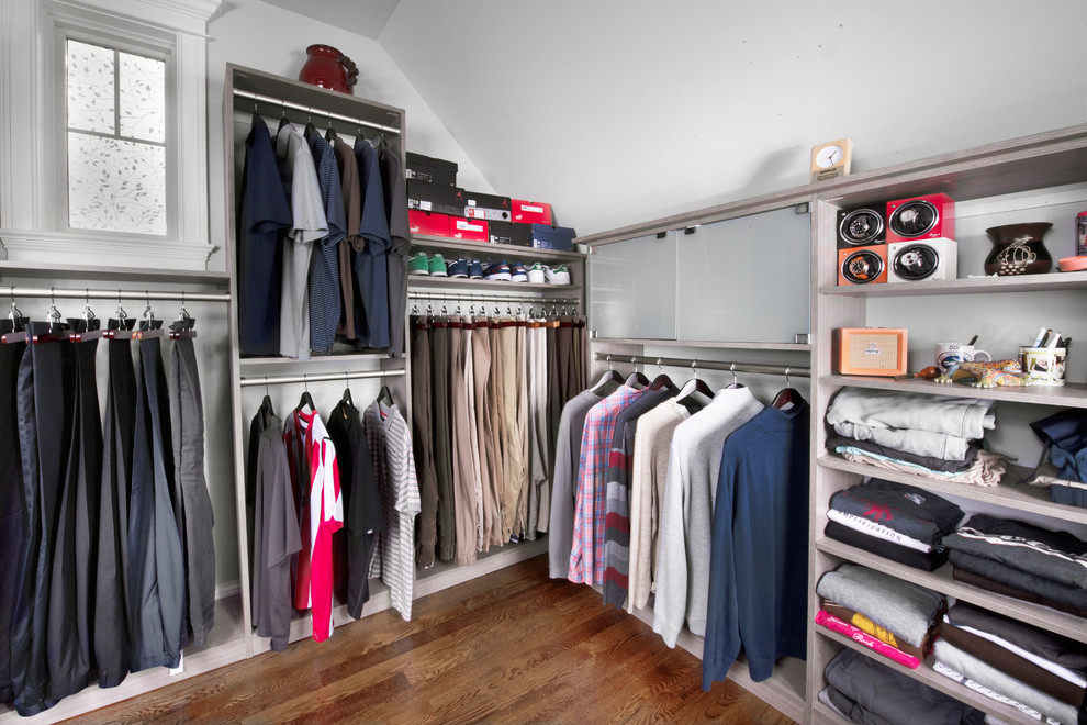 Modelo de armario vestidor unisex clásico renovado grande con armarios estilo shaker, puertas de armario grises, suelo de madera en tonos medios y suelo marrón