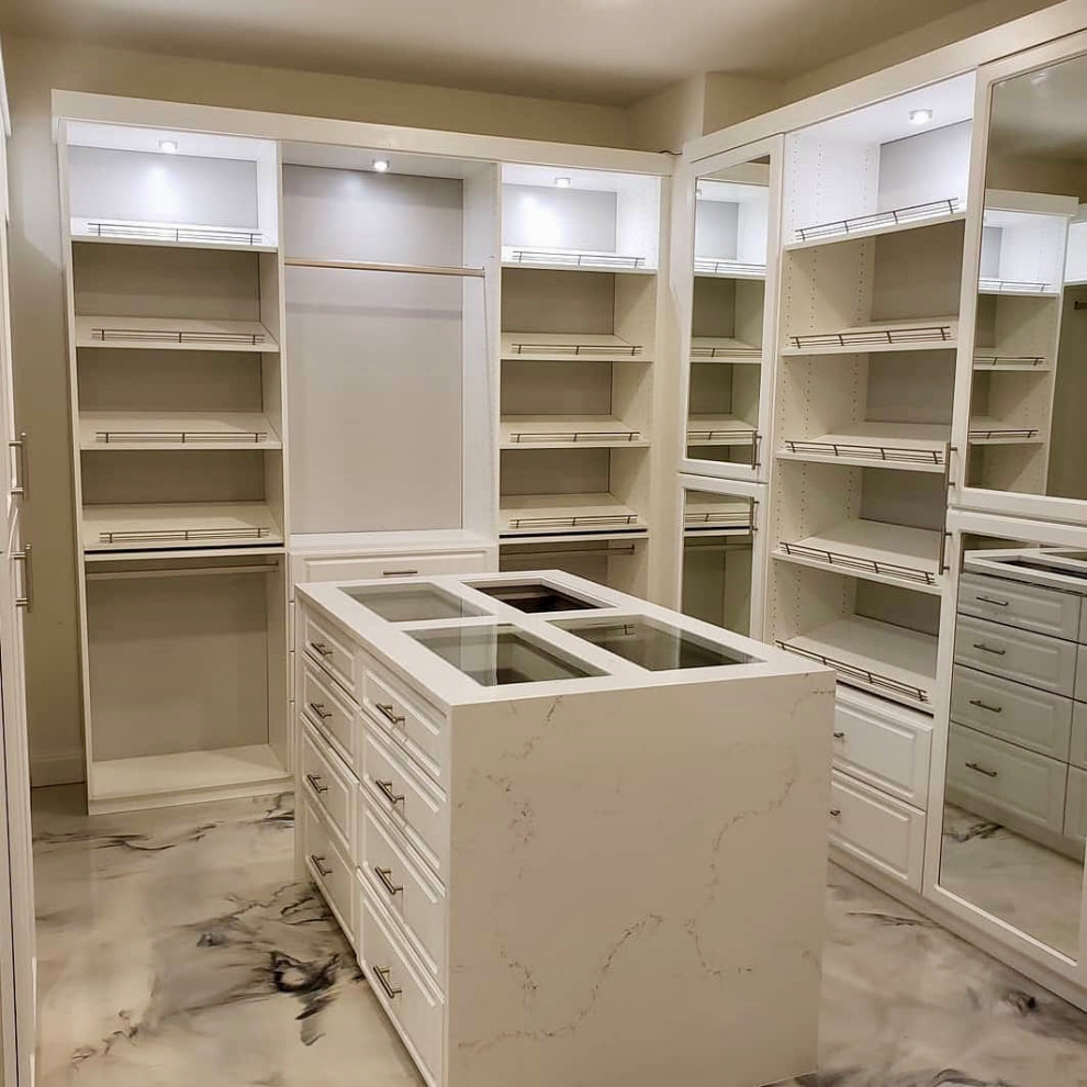 Ejemplo de armario vestidor unisex actual grande con armarios con paneles con relieve y suelo de mármol