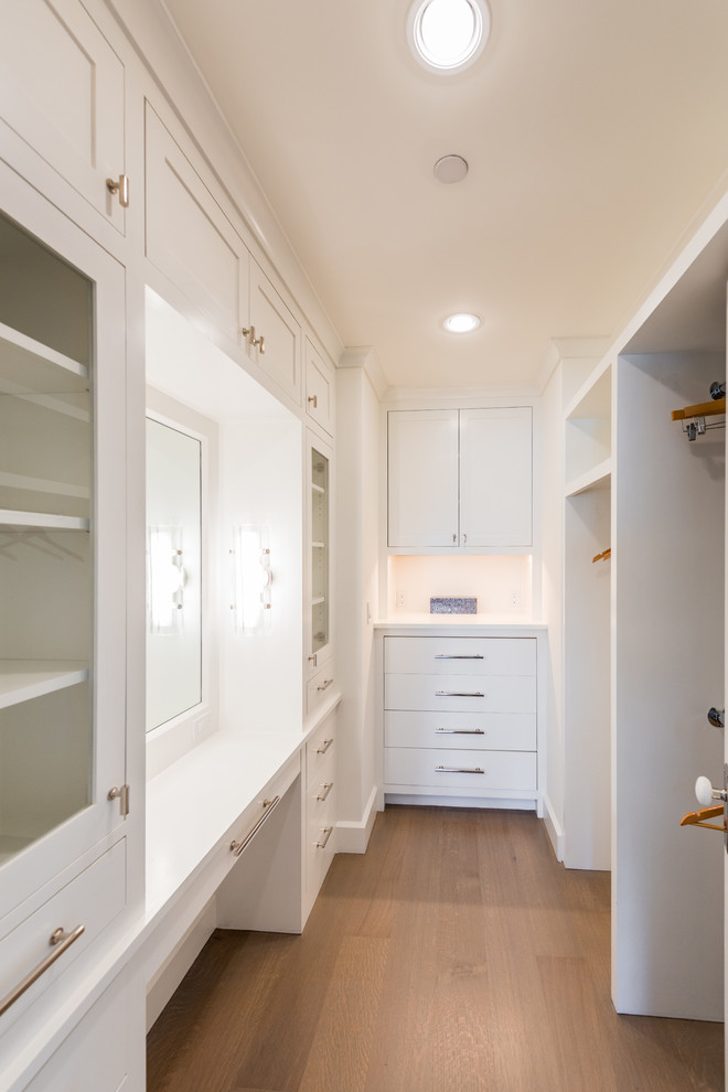 Small beach style gender-neutral light wood floor and beige floor walk-in closet photo in New York with recessed-panel cabinets and white cabinets