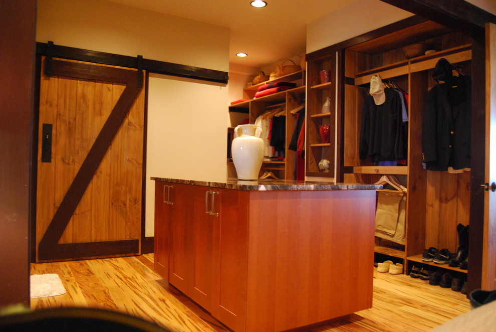 Diseño de vestidor unisex de estilo americano grande con armarios abiertos, puertas de armario de madera en tonos medios y suelo de madera oscura