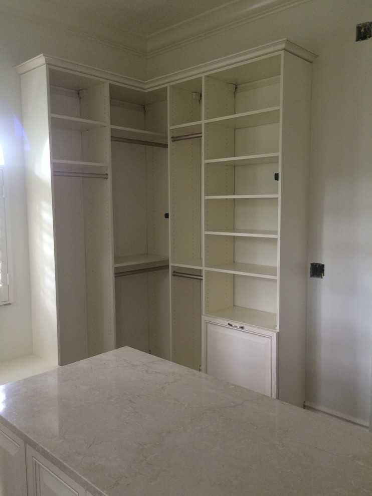 Large traditional gender neutral walk-in wardrobe in Miami with raised-panel cabinets, white cabinets and dark hardwood flooring.