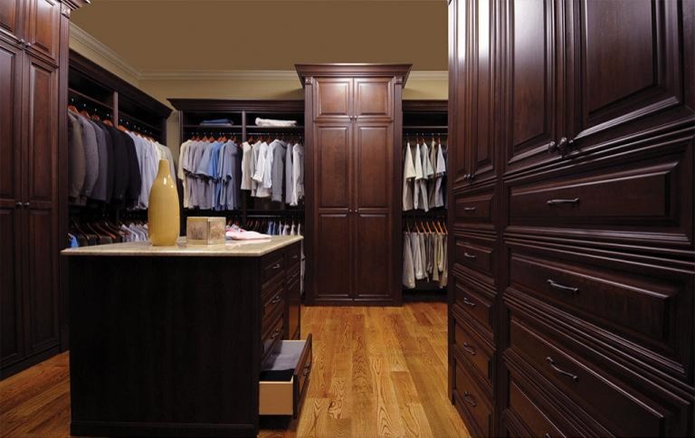 Imagen de vestidor unisex clásico grande con armarios con paneles con relieve, puertas de armario de madera en tonos medios, suelo de madera en tonos medios y suelo marrón
