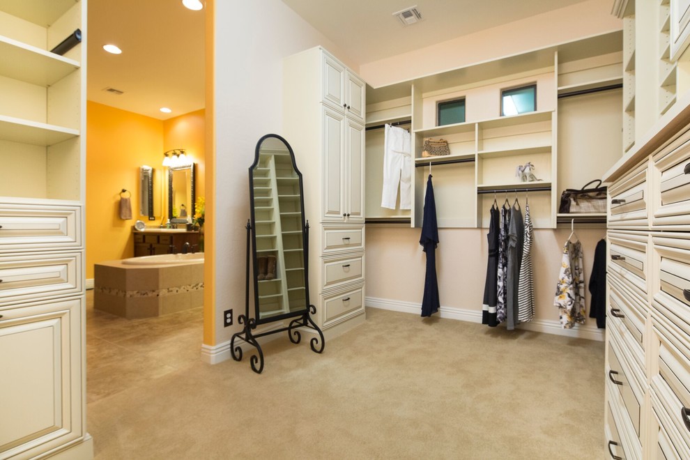 Design ideas for a large traditional gender neutral walk-in wardrobe in San Diego with beaded cabinets, white cabinets, carpet and beige floors.