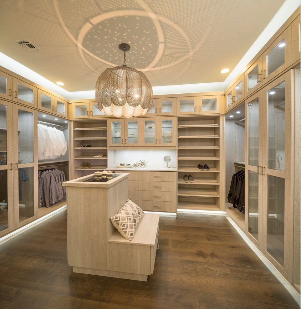 Example of a large trendy gender-neutral dark wood floor and brown floor walk-in closet design in San Diego with flat-panel cabinets and light wood cabinets