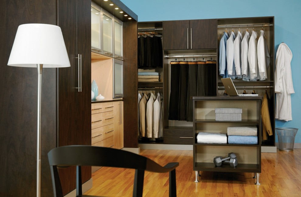 Diseño de armario vestidor unisex clásico grande con armarios con paneles lisos, puertas de armario de madera en tonos medios y suelo de madera clara