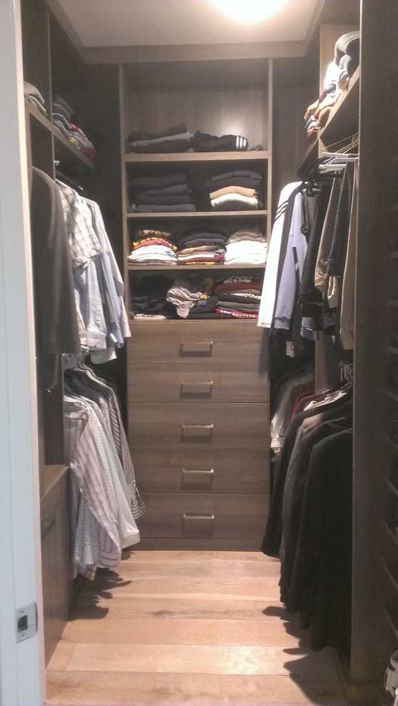 Imagen de armario vestidor de hombre contemporáneo de tamaño medio con armarios con paneles lisos, puertas de armario de madera en tonos medios, suelo de madera clara y suelo marrón
