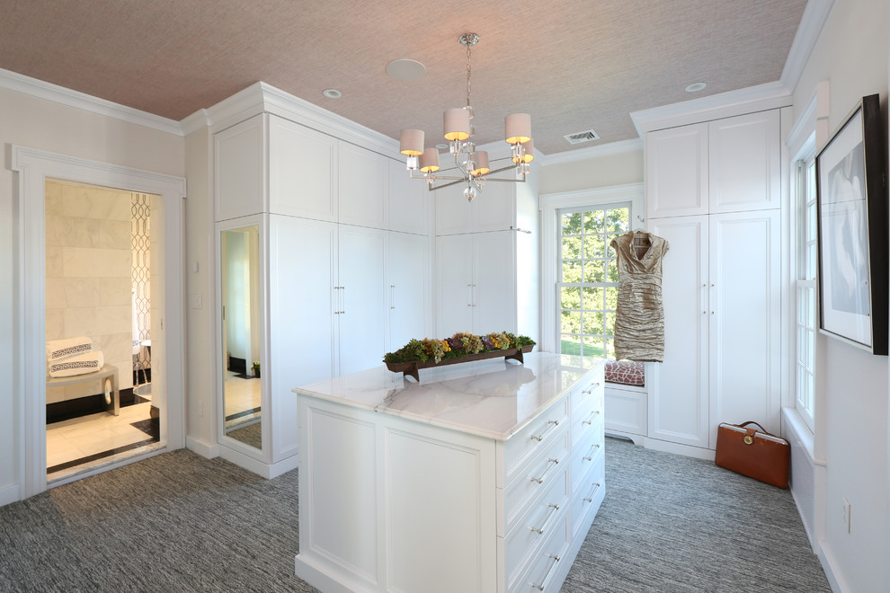 Aménagement d'un grand dressing room classique neutre avec des portes de placard blanches, moquette et un sol gris.