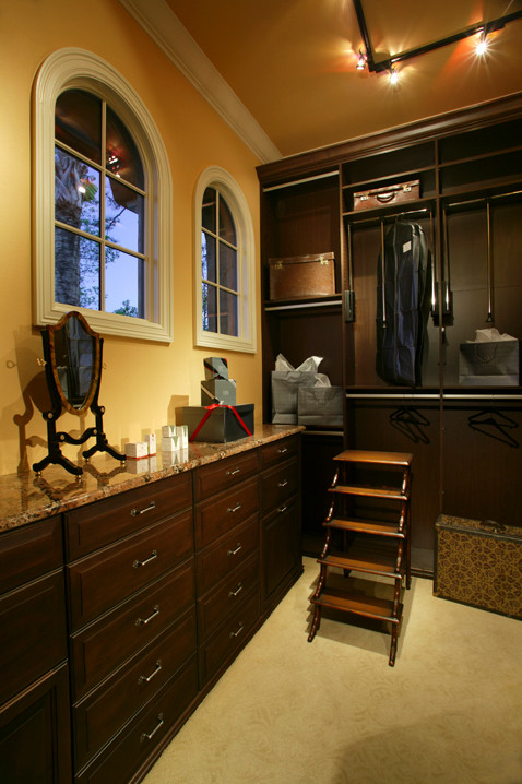 Immagine di un grande spazio per vestirsi per uomo classico con ante con bugna sagomata, ante in legno scuro, moquette e pavimento beige
