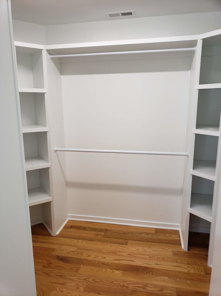 Imagen de armario vestidor unisex actual de tamaño medio con armarios abiertos, puertas de armario blancas, suelo de madera en tonos medios y suelo marrón