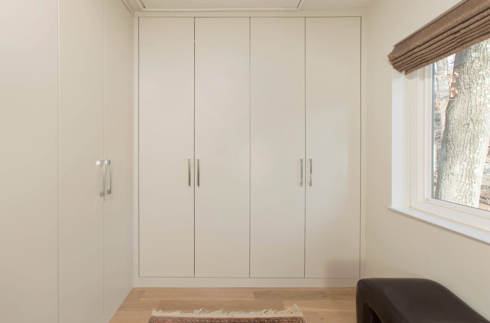 Diseño de vestidor unisex actual grande con armarios con paneles lisos, puertas de armario grises y suelo de madera clara