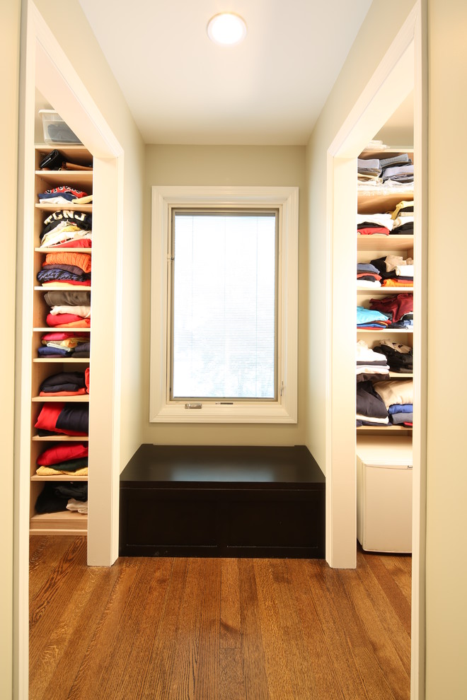 Modelo de armario vestidor unisex contemporáneo grande con armarios con paneles lisos, suelo de madera en tonos medios y puertas de armario beige