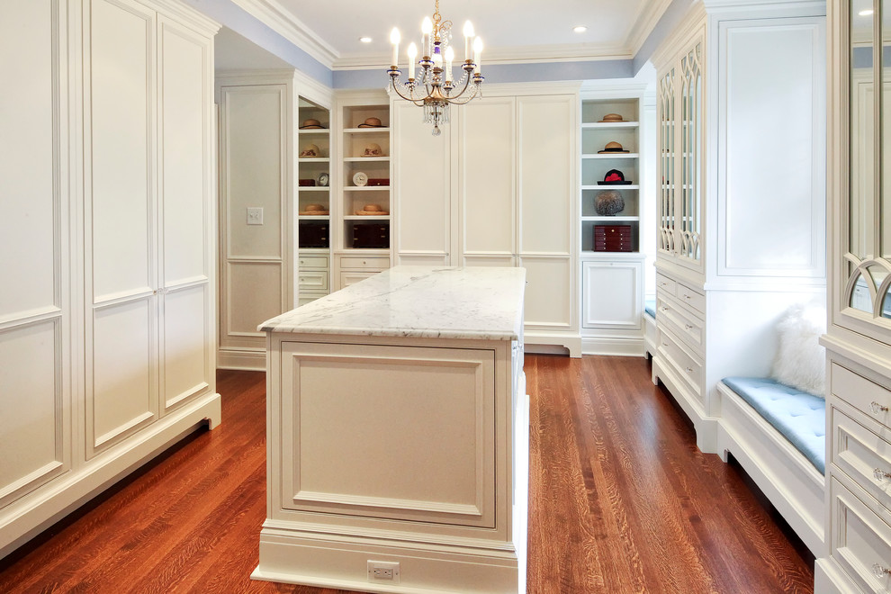 This is an example of a large traditional gender neutral dressing room in New York with beaded cabinets, white cabinets and medium hardwood flooring.