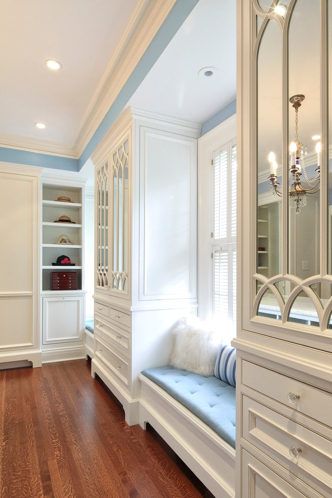 Exemple d'un dressing room chic neutre avec un placard à porte affleurante, des portes de placard blanches et un sol en bois brun.