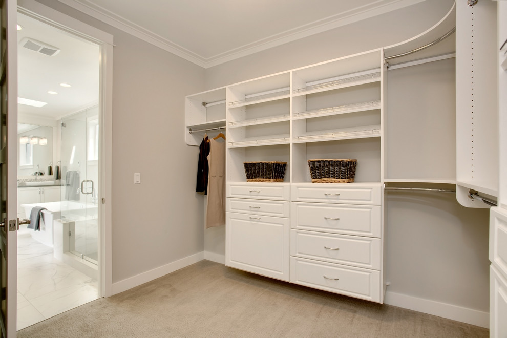 Inspiration for a traditional walk-in wardrobe in Seattle with raised-panel cabinets, white cabinets and carpet.