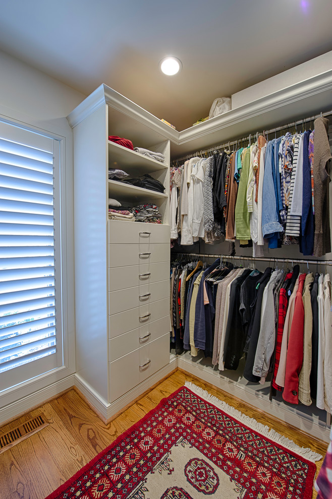 Ejemplo de armario vestidor de mujer clásico con armarios con paneles lisos, puertas de armario blancas y suelo de madera en tonos medios