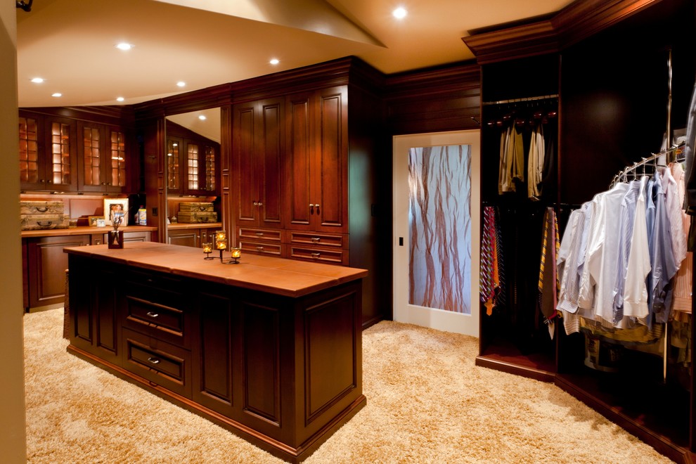 Design ideas for an expansive classic gender neutral dressing room in Boston with raised-panel cabinets, medium wood cabinets and carpet.