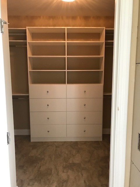 Example of a mid-sized classic gender-neutral beige floor and carpeted walk-in closet design in Other with flat-panel cabinets and white cabinets