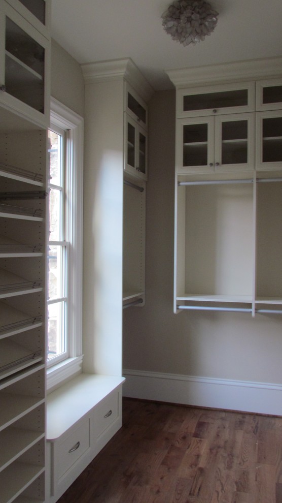 На фото: гардеробная комната среднего размера, унисекс в классическом стиле с стеклянными фасадами, белыми фасадами и паркетным полом среднего тона с