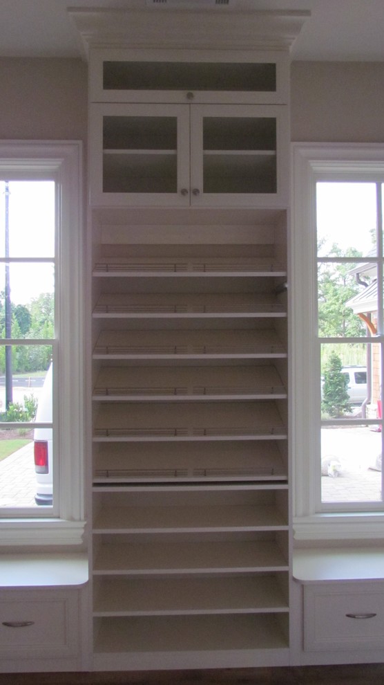 Ejemplo de armario vestidor unisex tradicional de tamaño medio con armarios tipo vitrina, puertas de armario blancas y suelo de madera en tonos medios