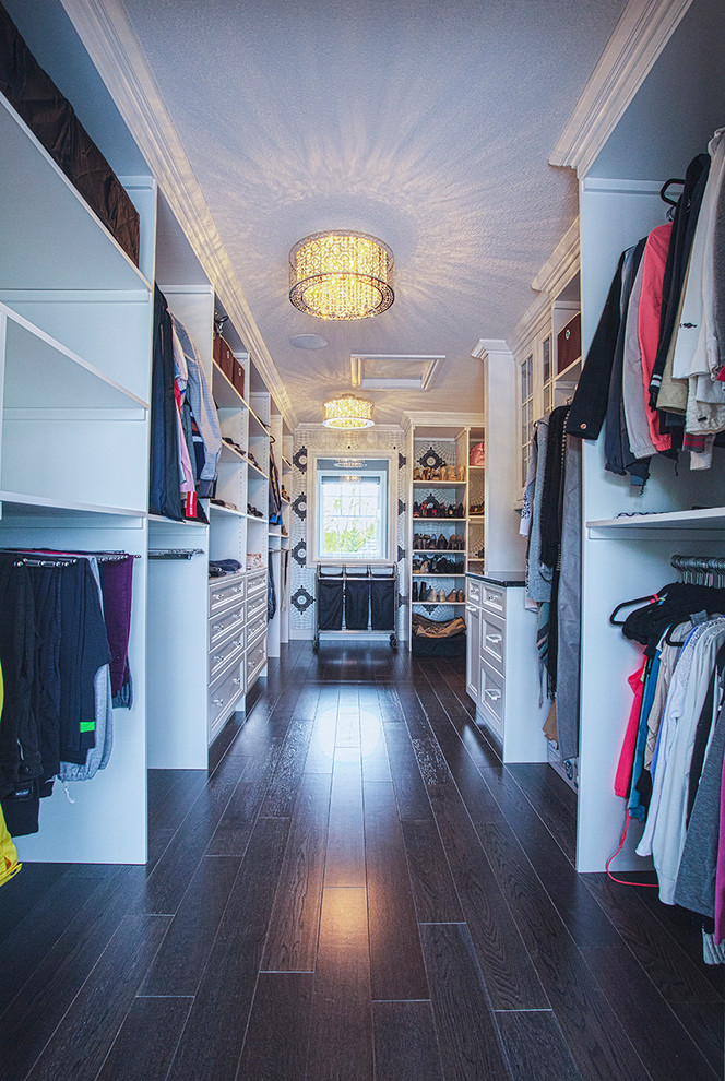 Imagen de armario vestidor unisex de estilo americano grande con armarios estilo shaker, puertas de armario blancas, suelo de madera oscura y suelo marrón