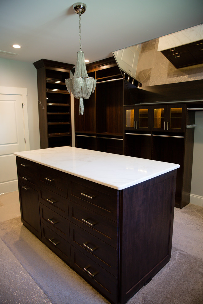 Photo of a large classic gender neutral walk-in wardrobe in Atlanta with shaker cabinets, dark wood cabinets, carpet and beige floors.