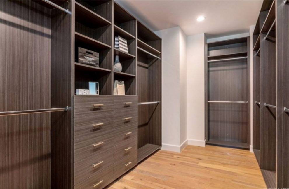 Large elegant light wood floor and brown floor walk-in closet photo in Los Angeles with flat-panel cabinets and medium tone wood cabinets
