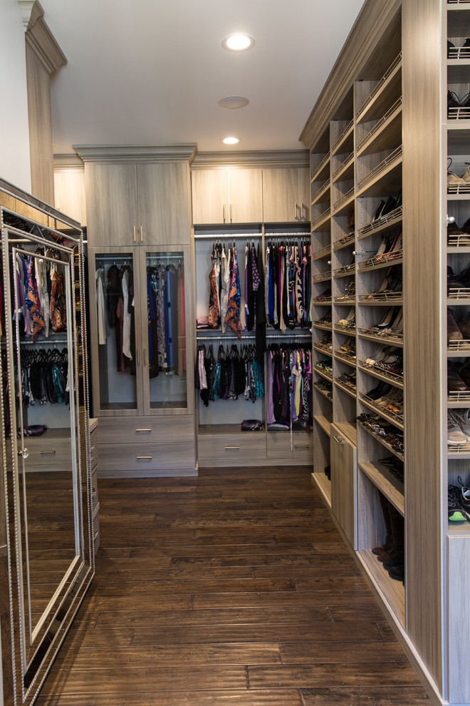 Modern inredning av ett stort walk-in-closet för kvinnor, med släta luckor, grå skåp, mörkt trägolv och brunt golv