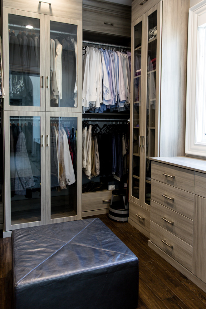 Imagen de armario vestidor de mujer actual grande con armarios con paneles lisos, puertas de armario grises, suelo de madera oscura y suelo marrón