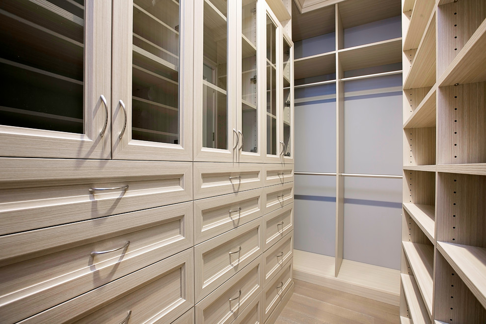Example of a small trendy walk-in closet design in New York with glass-front cabinets and light wood cabinets