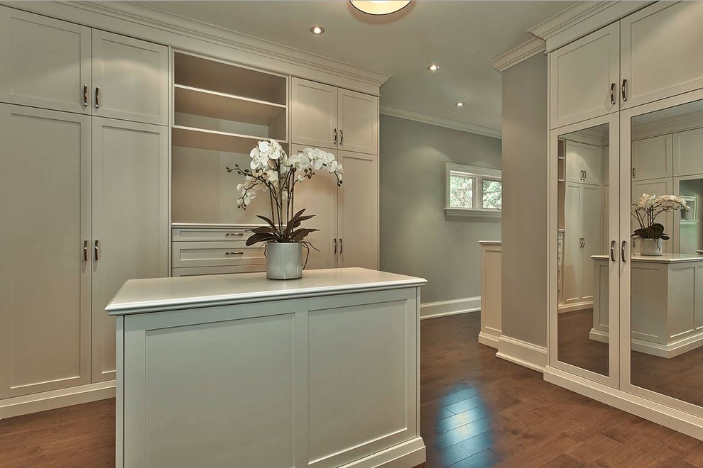 This is an example of a large classic gender neutral dressing room in Toronto with shaker cabinets, white cabinets and medium hardwood flooring.