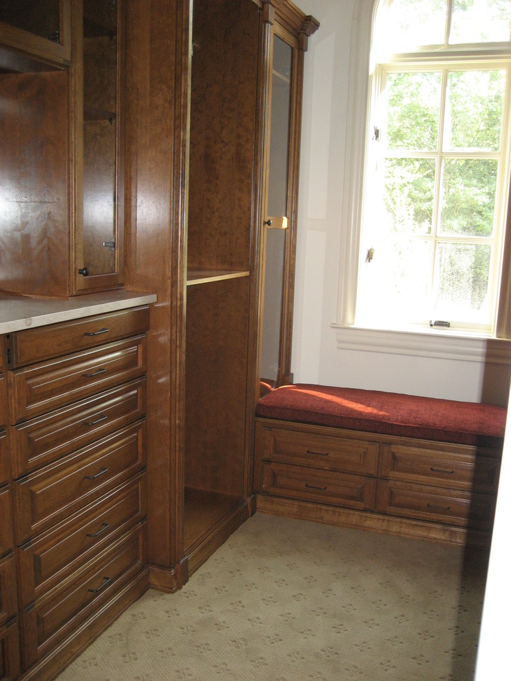 Imagen de armario vestidor unisex tradicional de tamaño medio con armarios con paneles con relieve, puertas de armario de madera en tonos medios y moqueta