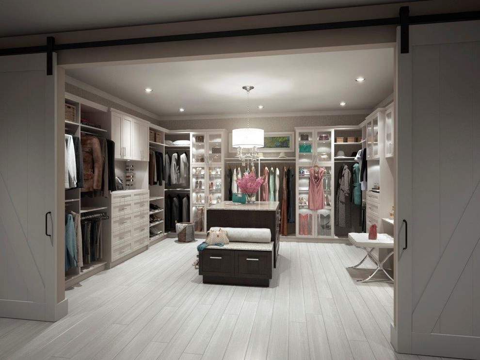На фото: большая гардеробная комната в стиле кантри с фасадами в стиле шейкер, белыми фасадами и светлым паркетным полом для женщин