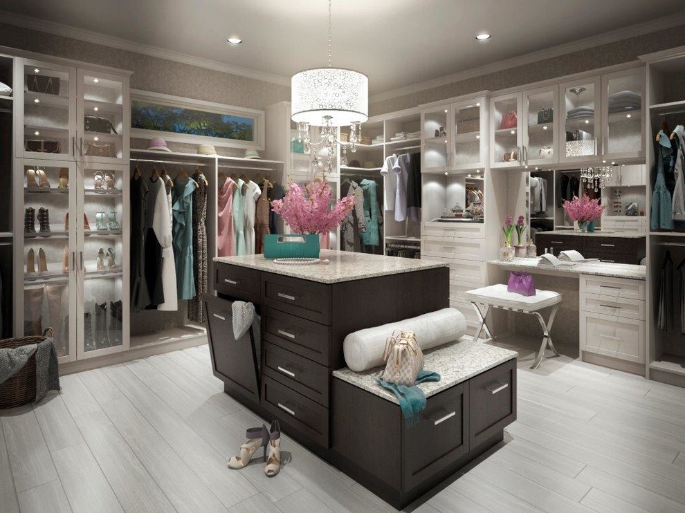 Large traditional walk-in wardrobe for women in Vancouver with shaker cabinets, white cabinets and light hardwood flooring.