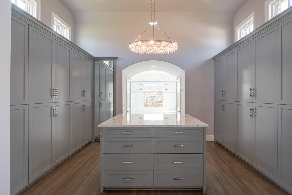 Design ideas for a large traditional gender neutral dressing room in Dallas with shaker cabinets, grey cabinets, medium hardwood flooring and brown floors.