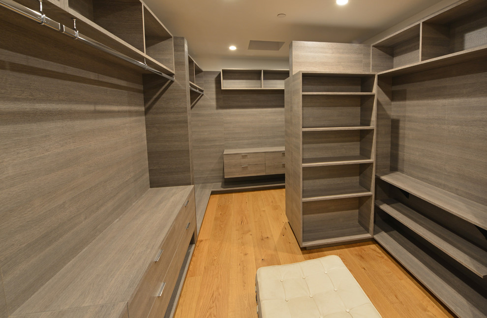 Bild på ett stort funkis walk-in-closet för könsneutrala, med öppna hyllor, grå skåp, ljust trägolv och brunt golv
