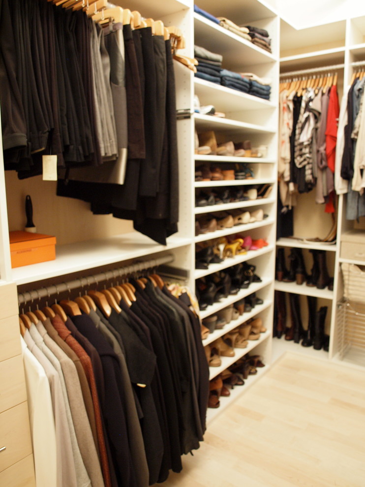 Photo of a large contemporary gender neutral walk-in wardrobe in New York with light wood cabinets and light hardwood flooring.