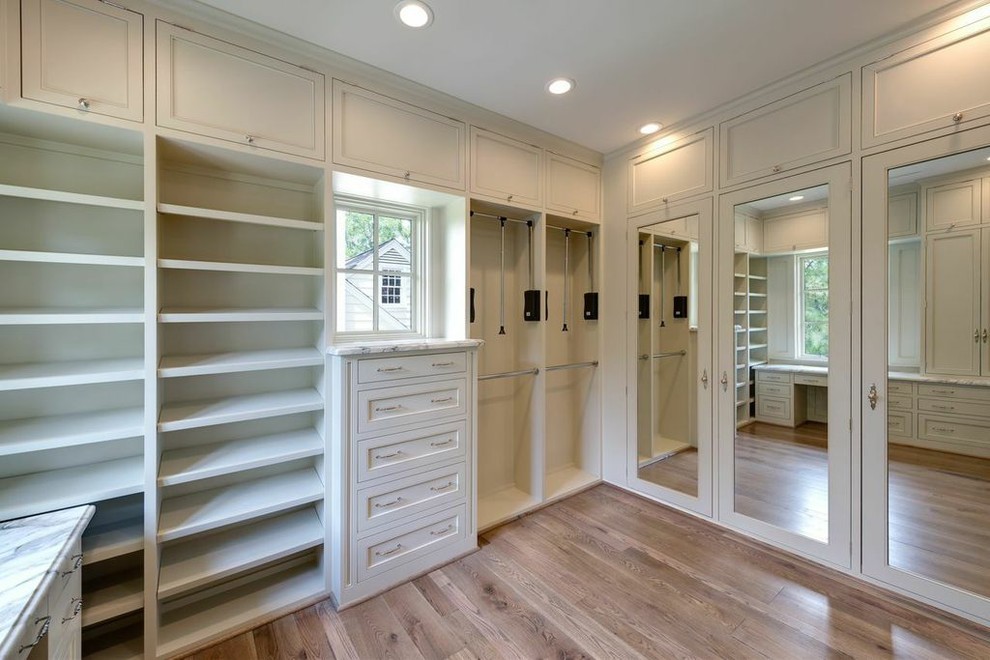 Large tuscan women's medium tone wood floor walk-in closet photo in Houston with gray cabinets