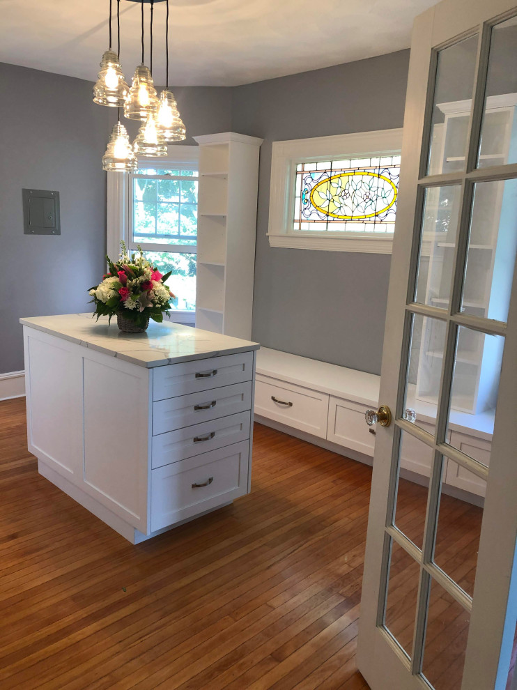Inspiration for a large traditional gender neutral dressing room in Boston with shaker cabinets, white cabinets, medium hardwood flooring and brown floors.