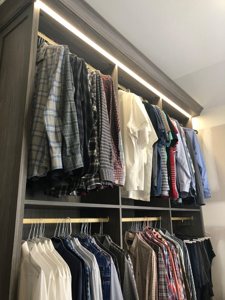 Photo of a large modern walk-in wardrobe for men in New York with flat-panel cabinets, grey cabinets, carpet and blue floors.
