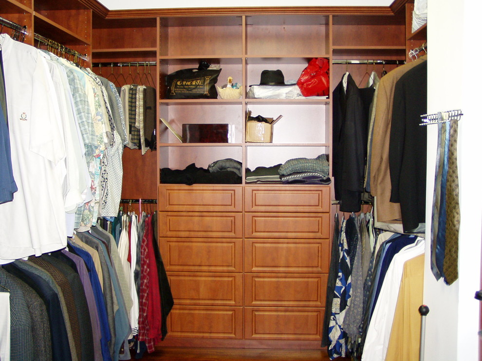 Ejemplo de armario vestidor unisex tradicional de tamaño medio con armarios con paneles con relieve y puertas de armario de madera oscura