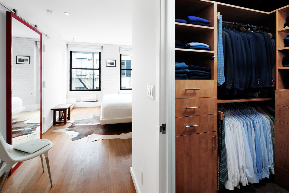 Example of a minimalist medium tone wood floor closet design in New York